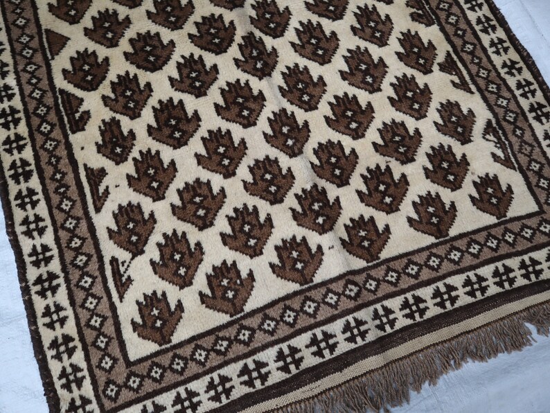 May include: A brown and white patterned rug with a geometric design. The rug has a fringe border.