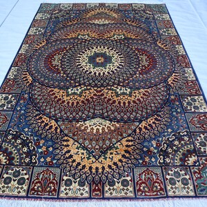 May include: A rectangular rug with an intricate floral design. The rug features a central medallion in shades of blue, brown, and gold, surrounded by a border with repeating patterns. The rug has a fringe along the edges.