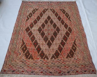 May include: A rectangular woven rug featuring a central field of dark brown and red diamonds on a light beige background. The border displays intricate geometric patterns in red, black, and tan, finished with a short fringe on both ends.