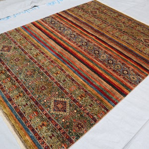 May include: A colorful rug with a striped pattern and intricate geometric designs in shades of red, blue, green, and gold.