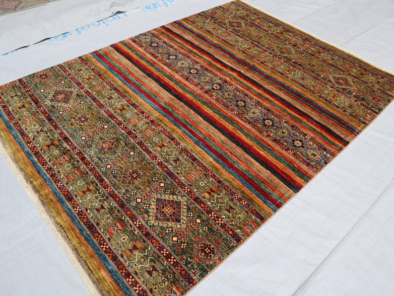 May include: A colorful rug with a striped pattern and intricate geometric designs in shades of red, blue, green, and gold.