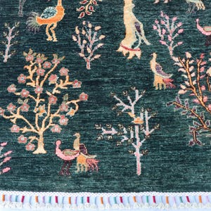 May include: A green rug with a floral and bird design. The rug has a fringe border and features pink, orange, and yellow accents.