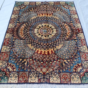 May include: A rectangular, intricately patterned rug with a central medallion design. The rug features a rich color palette of blues, reds, and golds, with a detailed floral and geometric pattern. The rug has a fringe along the edges.