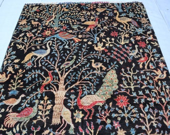 May include: A black rug with a detailed design of trees, birds, and flowers. The rug features a variety of colors, including blue, red, green, and yellow.