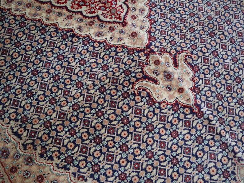 Puede incluir: Primer plano de una alfombra estampada con un esquema de color azul, rojo y crema. La alfombra tiene un dise&ntilde;o floral con detalles intrincados.