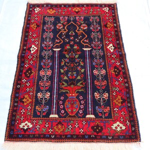 May include: A traditional Turkish prayer rug with a dark blue background and intricate floral patterns in red, orange, yellow, and blue. The rug features two stylized trees with a vase at the base.