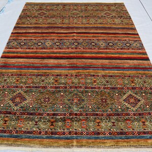 May include: A colorful rug with a geometric pattern in shades of red, green, blue, and brown. The rug has a fringe border.