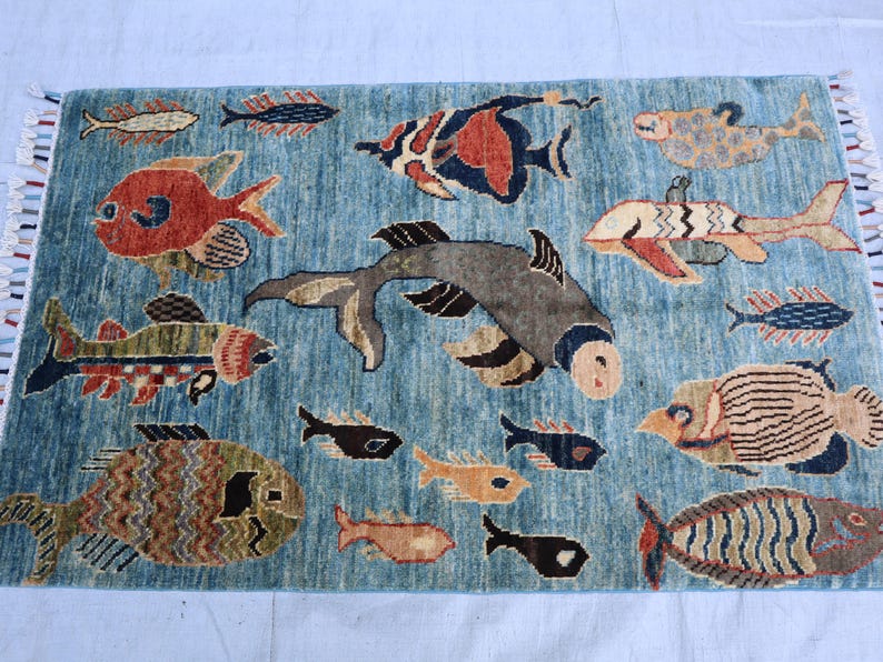 May include: A blue rug with a colorful fish design. The rug features a variety of fish in different colors and patterns, including red, orange, yellow, green, blue, and black. The rug is made of wool and has a soft, plush texture.