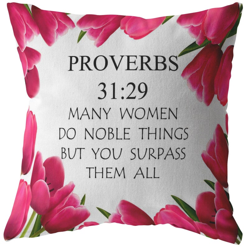 May include: A white pillow with pink tulips printed on the front. The pillow has the text "Proverbs 31:29 Many women do noble things but you surpass them all" printed in black.