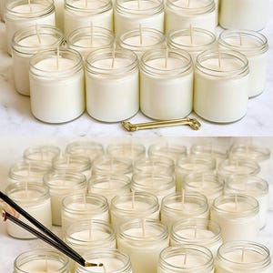 a collection of glass jars filled with white candles, arranged on a marble surface.