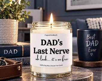 Może przedstawiać: Płonąca świeca z wosku sojowego w przezroczystym szklanym słoiku z białą etykietą z czarnym napisem: FragrantCandlesUS, DAD's Last Nerve, oh look.... it's on fire, 100% Soy Wax, Choose Your Scent. Świeca stoi na ciemnoszarej kamiennej powierzchni.
