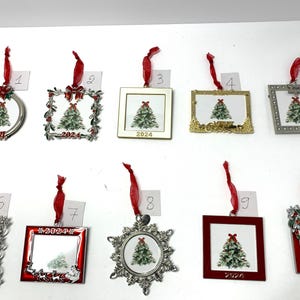May include: A collection of ten Christmas tree ornaments with red ribbons. Each ornament features a Christmas tree design and the year 2024. The ornaments have various frame styles, including circles, squares, and ornate designs.