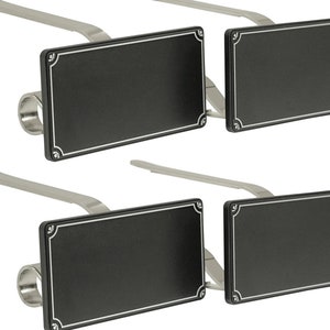 May include: Set of four black metal sign holders with a silver finish. Each holder has a rectangular sign with a white border and a decorative design in the corners.