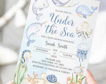 Può includere: Un invito per un baby shower a tema "Sotto il Mare". L'invito presenta illustrazioni ad acquerello di animali marini come balene, delfini e un polpo. Il testo include i dettagli dell'evento: data, ora e informazioni RSVP.