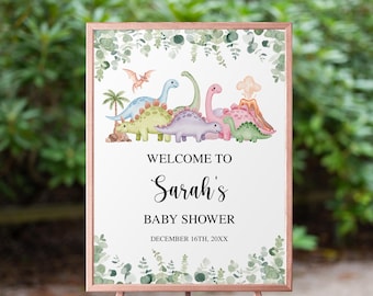 Könnte beinhalten: Ein Babyparty-Schild mit einem roségoldenen Rahmen und Ständer. Das Schild zeigt eine Aquarellillustration von bunten Dinosauriern, einem Vulkan und Palmen. Der Text lautet "Willkommen zu Sarahs Babyparty".