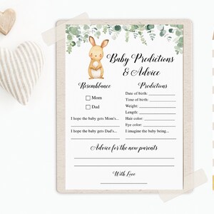 May include: A printable baby shower game card with a cute bunny illustration. The card has sections for guests to write predictions about the baby's birth details, resemblance to parents, and advice for the new parents. The text on the card reads "Baby Predictions & Advice".