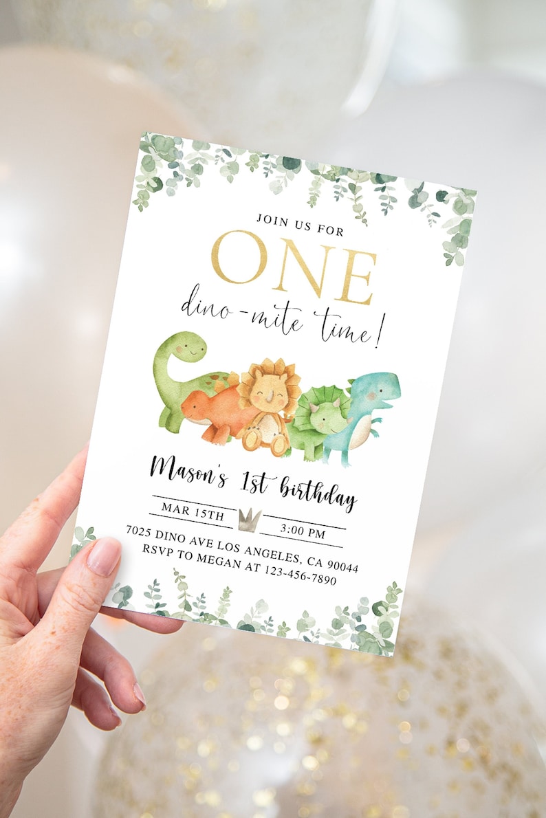 K&ouml;nnte beinhalten: Eine wei&szlig;e Einladungskarte mit gr&uuml;nem Bl&auml;tterrand. Der Text lautet "Join us for One dino-mite time! Mason's 1st birthday Mar 15th 3:00 PM 7025 Dino Ave Los Angeles, CA 90044 RSVP to Megan at 123-456-7890". Die Karte zeigt eine goldene Krone und eine Gruppe von Comic-Dinosauriern.