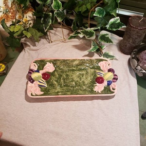 May include: A rectangular ceramic serving tray with a green and pink design. The tray features a green pine tree design with pink bows and colorful ornaments.