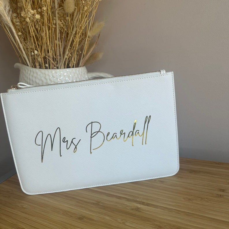 May include: White zippered pouch with a gold inscription that reads "Mrs. Beardall".