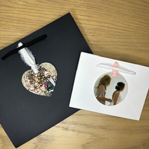 Peut inclure: Deux sacs cadeaux blancs avec des poign&eacute;es en ruban noir et rose. Un sac a une photo en forme de c&oelig;ur d'un couple devant un fond de confettis. L'autre sac a une photo ronde de deux personnes en robe blanche et en robe blanche.