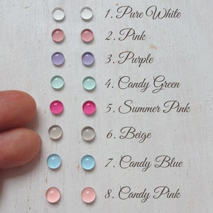 May include: Eight colour swatches of round, translucent, flat, glass-like beads. The colours are: pure white, pink, purple, candy green, summer pink, beige, candy blue, and candy pink.