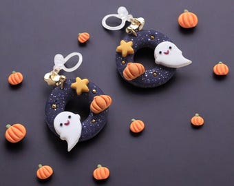 以下が含まれることがあります： ハロウィーンをテーマにしたイヤリング。濃い青色のリングデザインで、おばけ、カボチャ、星が特徴です。イヤリングは金色のアクセントで飾られ、暗い背景にミニチュアのオレンジ色のカボチャが散りばめられています。