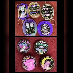 May include: A collection of ten resin keychains with various designs. The keychains feature a variety of colors, including purple, pink, black, white, and green. The keychains have different designs, including a skull, a coffin, a spider, a cat, and a ghost. The keychains have text on them, including "Kawaii but Kowai", "Creepy but Cute", "Dead Cute", "I Have Anxiety", "Stay Weird", and "You Disgust Me".