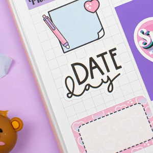 May include: A collection of colorful planner stickers with various designs, including a heart with the word "Mon" and the text "Planner Things", a blue note with a pink pen, a white sticker with the text "DATE day", a purple sticker with a pink heart and the text "Speak up!" and a pink sticker with a white border and a heart pattern.