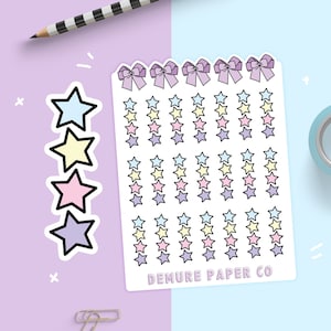 May include: A sheet of pastel-colored star stickers with a bow design at the top. The sheet is white with a black outline around the stars and bows. The text "DEMURE PAPER CO" is printed at the bottom of the sheet.