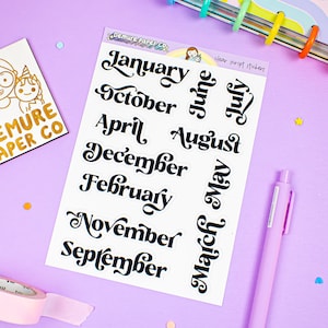 May include: A sheet of clear script stickers with the months of the year written in black cursive lettering. The months are January, February, March, April, May, June, July, August, September, October, November, and December.