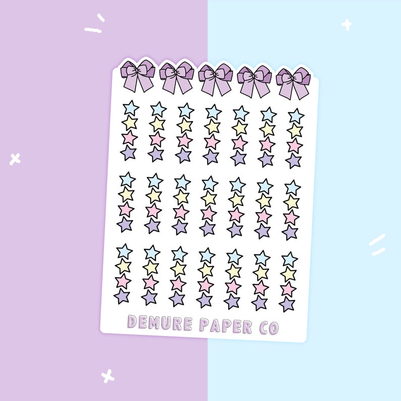 May include: A sheet of colorful star stickers with a pink, yellow, and blue color scheme. The sheet has a scalloped edge and features four bows at the top. The text "DEMURE PAPER CO" is printed at the bottom of the sheet.
