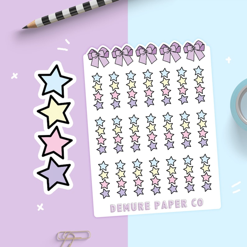 May include: A sheet of pastel-colored star stickers with a bow design at the top. The sheet is white with a black outline around the stars and bows. The text "DEMURE PAPER CO" is printed at the bottom of the sheet.