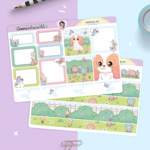 May include: Two sheets of planner stickers with a pastel theme. The stickers feature a cartoon Cavalier King Charles Spaniel, butterflies, flowers, and decorative boxes. The text "Demure Paper Co." is visible on one sheet. The stickers are designed for vertical planners.