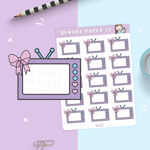 May include: A sheet of stickers featuring a cartoon television with a pink bow and a heart. The stickers are on a light blue background with the text "DEMURE PAPER CO" and "S022".