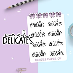 May include: A sheet of stickers with the text "wash delicates" repeated six times. Each sticker features a purple bow. The bottom sticker has the text "DEMURE PAPER CO" below the text "wash delicates".