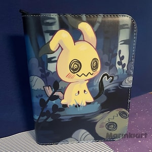Op de afbeelding: Een portemonnee met ritssluiting met een cartoon Mimikyu-personage in een bos. De Mimikyu is geel met zwarte accenten en een zwarte staart. De achtergrond is donkerblauw met bomen en rotsen. De handtekening van de kunstenaar, Marinklart, staat rechtsonder.