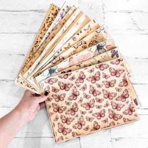 May include: A collection of vintage-style papers featuring butterfly illustrations in various colors, including pink, orange, and purple. The papers have a distressed, aged appearance, with a variety of butterfly patterns.