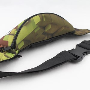 May include: A green and brown camouflage fanny pack with a black adjustable strap and a zipper closure.