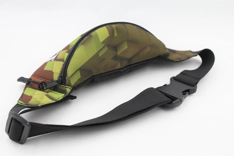 May include: A green and brown camouflage fanny pack with a black adjustable strap and a zipper closure.