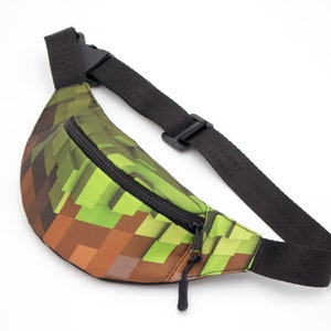May include: A green and brown pixelated fanny pack with a black adjustable strap and zipper.