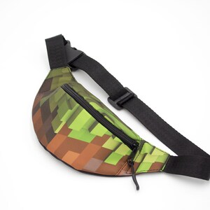 May include: A green and brown pixelated fanny pack with a black adjustable strap and zipper.