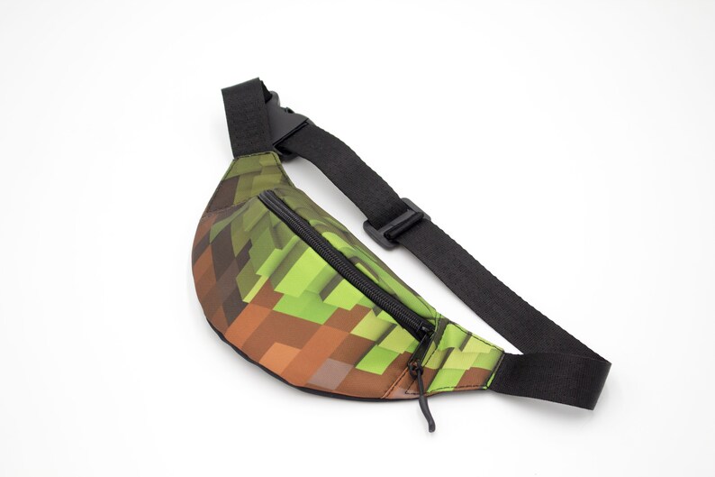 May include: A green and brown pixelated fanny pack with a black adjustable strap and zipper.