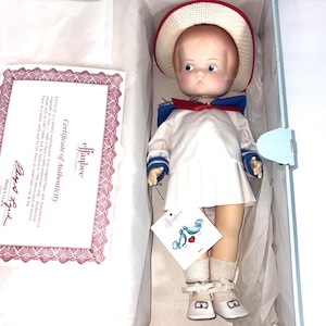 May include: An Effanbee Patsy doll in a white sailor outfit with a red-trimmed straw hat, blue collar, and white shoes. The doll is inside a box with a Certificate of Authenticity that reads: Patsy is a faithful reproduction of an original Patsy doll.