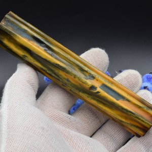 Puede incluir: Un blanco de bolígrafo con un patrón amarillo, azul y negro con una textura nervada. El blanco mide aproximadamente 25 cm de largo.