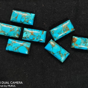 May include: Seven turquoise cabochons with gold flecks. The cabochons are rectangular and have a smooth, polished surface.