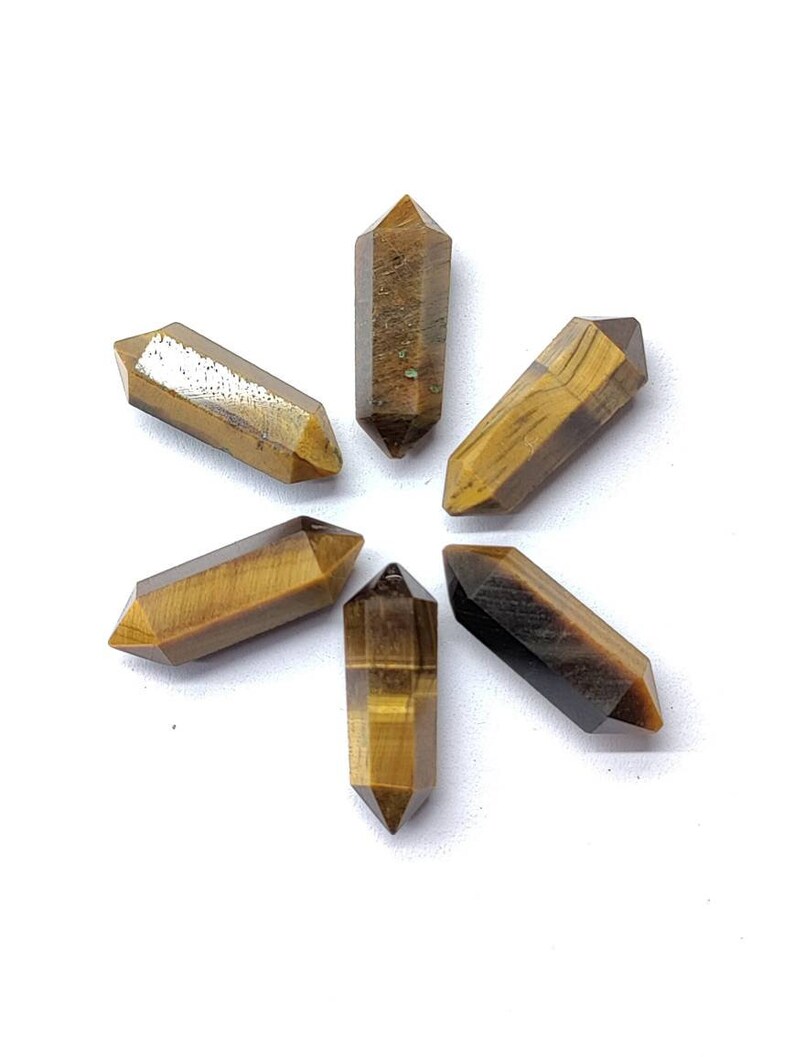 Close up of natural Tiger Eye pencil shape gemstone with golden brown bands and faceted surface