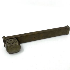 May include: A long, rectangular, brass-colored box with a smaller, square, brass-colored box attached to one end. The box is made of metal and has a smooth, polished finish.