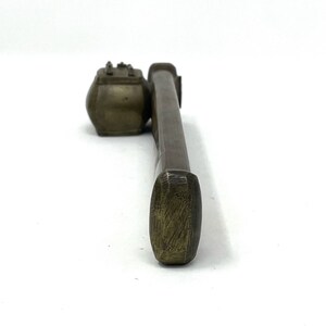 May include: A brass inkwell and brush set. The inkwell is a small, round container with a lid. The brush is long and thin with a rounded tip.