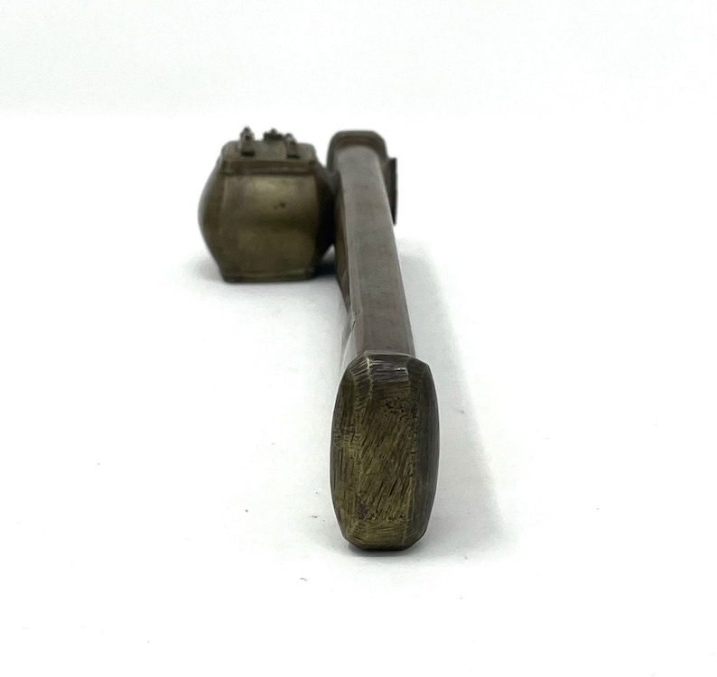 May include: A brass inkwell and brush set. The inkwell is a small, round container with a lid. The brush is long and thin with a rounded tip.