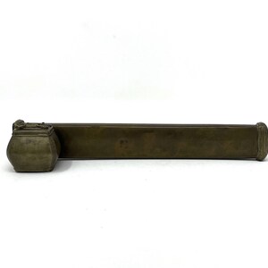 May include: A brass inkwell set with a rectangular container and a round inkwell. The inkwell is attached to the container.